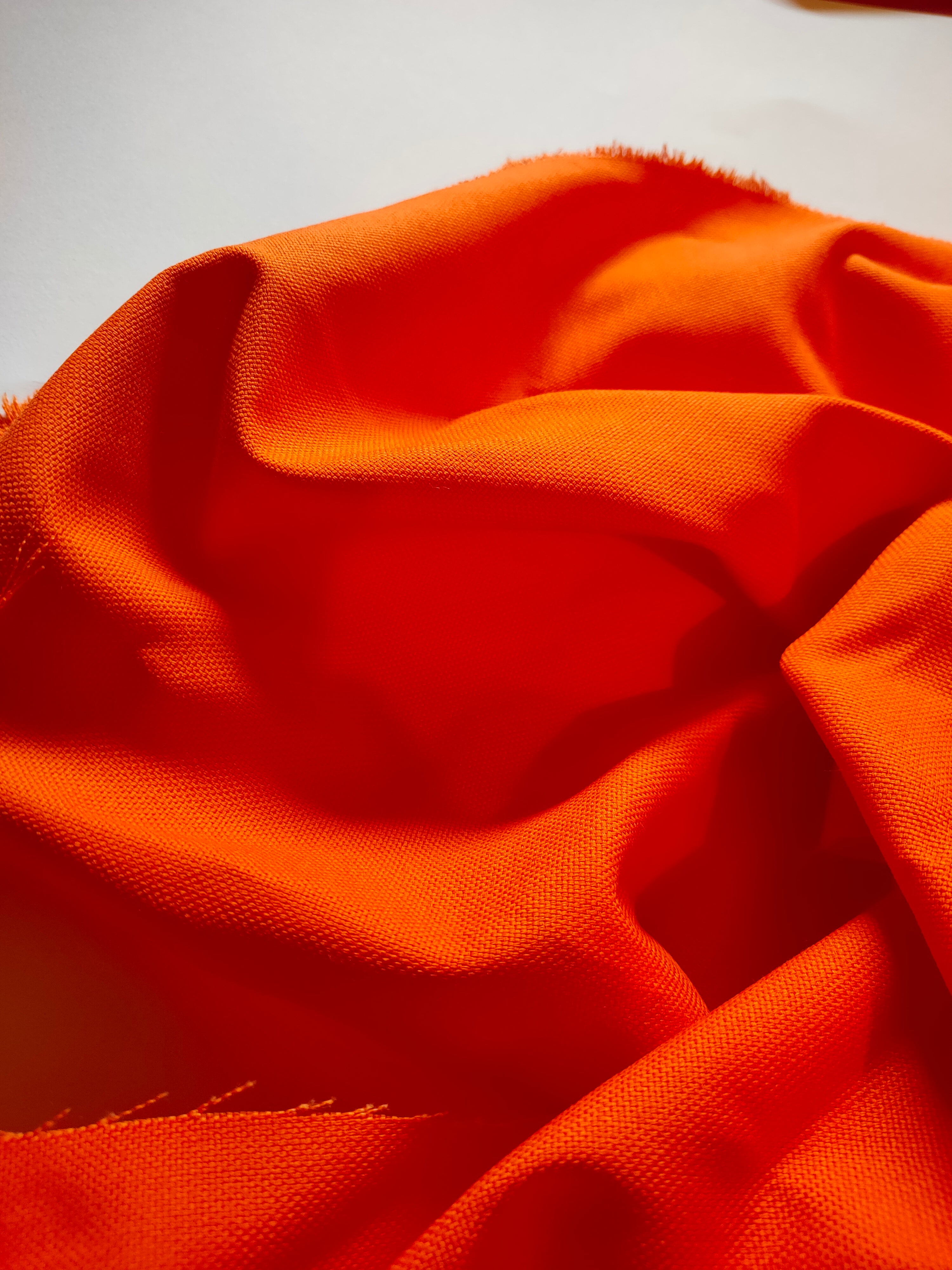 Toile de coton orange, détail de la matière en gros plan, effets de plis.